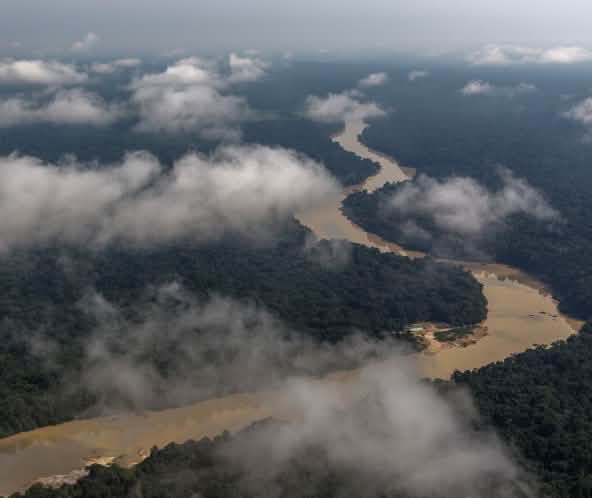Vista aérea con nubes de un río serpenteando por la selva tropical amazónica