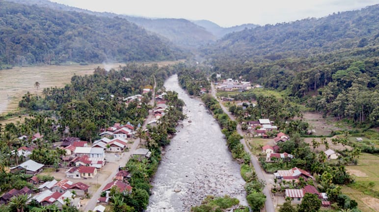 Río atraviesa un pueblo, al fondo se ven montañas