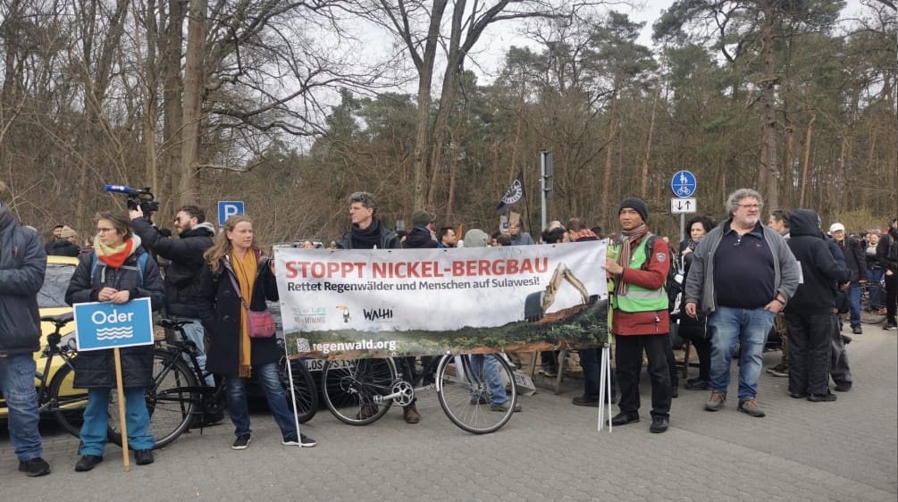 Pancarta "Detengan la minería de níquel", sostenida por Stefanie Hess und Boboy Simanjuntak junto a otros participantes en la protesta en contra de Tesla