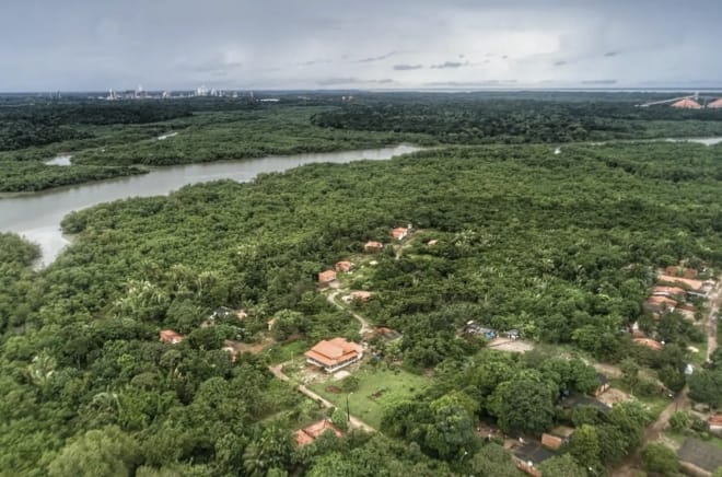 Vista aérea de casas entre la vegetación amazónica abundante y detrás un río con manglares en las orillas en Tauá Mirim, Maranhao, Brasil