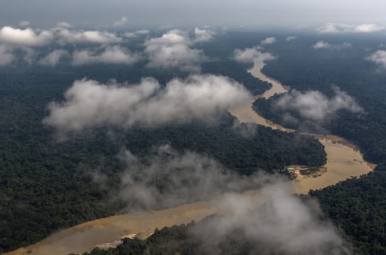 Vista aérea con nubes de un río serpenteando por la selva tropical amazónica