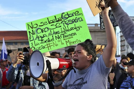 Mujer con megáfono durante las protestas en contra de la minería en Panamá, en 2023. Al fondo, una pancarta "El Agua, el Aire, la Naturaleza y la Salud, no tienen precio"