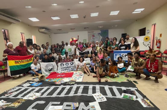 Foto de grupo de cerca de 50 personas con pancartas en una sala de reuniones