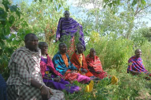 Un grupo de hombres masái sentados en la hierba  con coloridas vestimentas