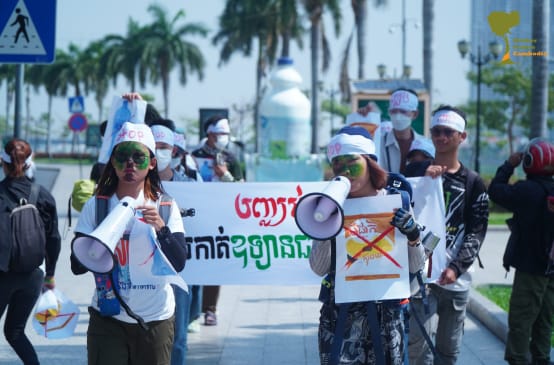 Un grupo de jóvenes estudiantes caminan por una calle portando megáfonos y pancartas