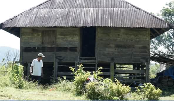 Una persona delante de una antigua casa de madera