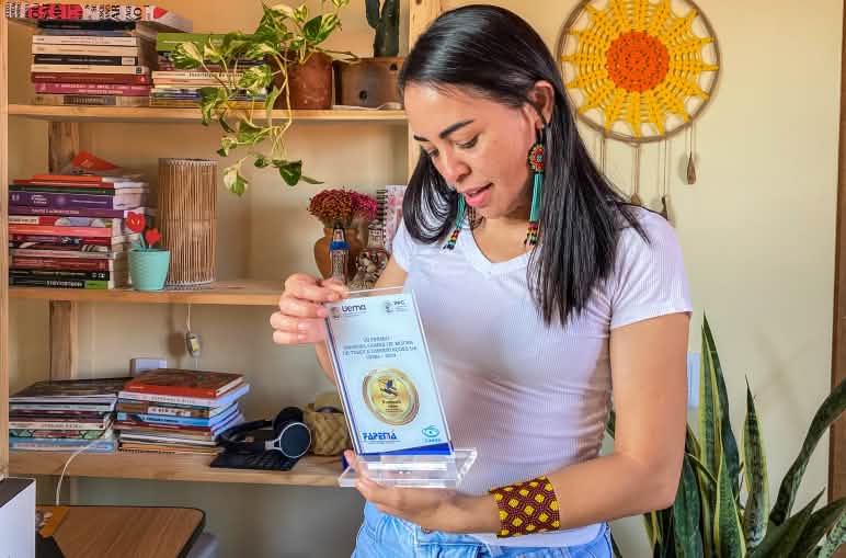 La antropóloga Ariana Gomes muestra la placa del premio recibido