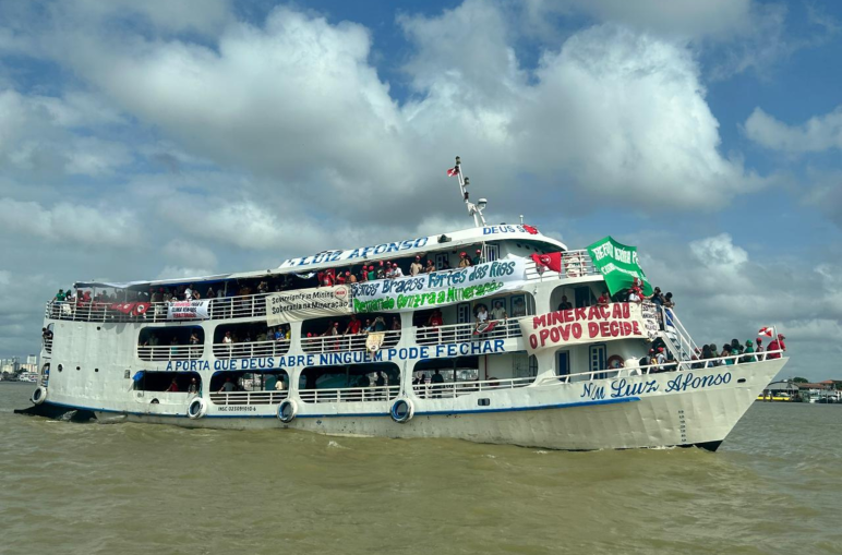 Una embarcación en el río, con pancartas en las que se leen mensajes como “Minería: el pueblo decide”