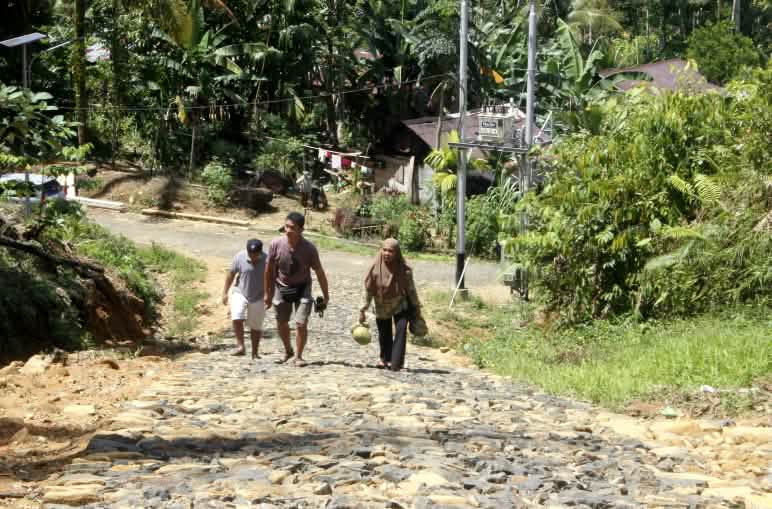 Tres personas en una carretera asfaltada en una aldea en el bosque