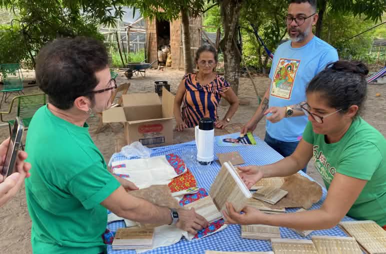 Dos mujeres mostrando cuadernos artesanales extendidos sobre una mesa, parte del emprendimiento de mujeres de la comunidad Centro da Josina, en Sao Luis Gonzaga, Maranhao