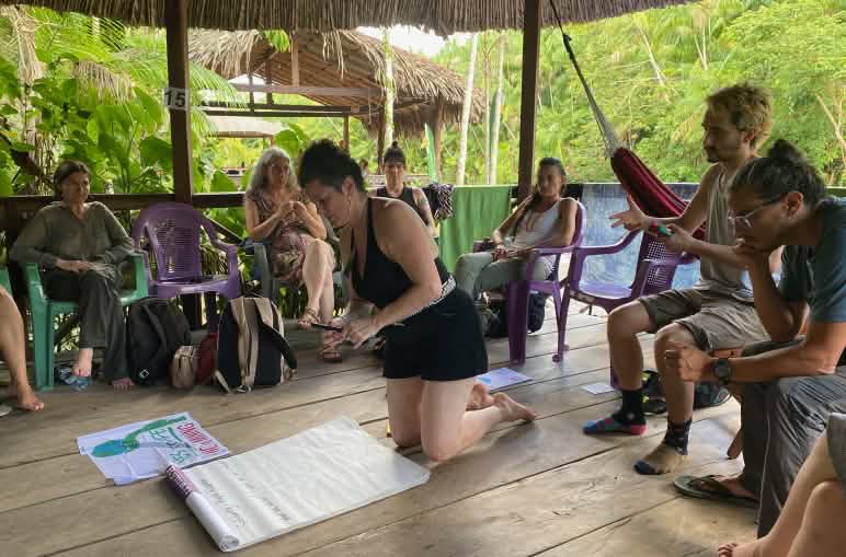 Grupo de ocho personas en un encuentro de planificación en una cabaña en la selva