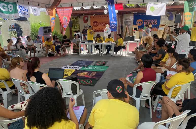 Una treintena de personas sentadas y formando un círculo en reunión