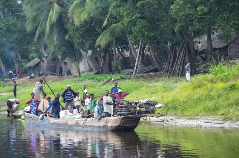Canoa llena de pasajeros y cargada con bicicletas en el río