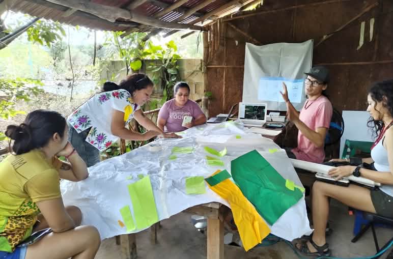 Mujeres trabajan alrededor de una mesa en actividades de conservación, mapeo y planificación