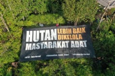 Gran pancarta con el mensaje "Indígenas, los mejores defensores de la selva", en idioma bahasa Indonesia