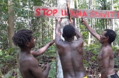Tres indígenas papúes con un cartel en defensa de su bosque