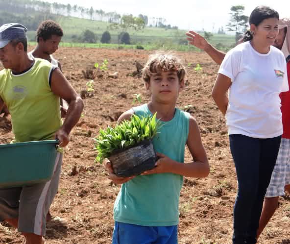 Un grupo de campesinos, entre los que destaca un niño que mira a la cámara en el centro de la imagen, en una jornada de trabajo a punto de sembrar