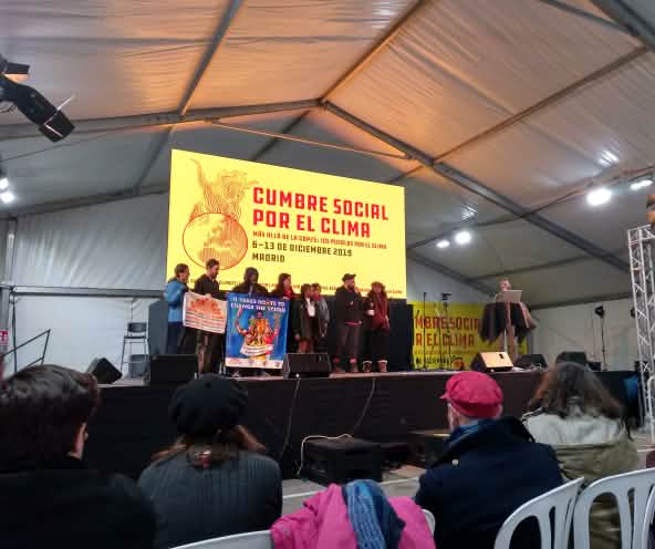 Cumbre social por el clima paralela a la COP25, en diciembre 2019 Madrid. Un grupo de personas sostienen pancartas sobre un escenario.