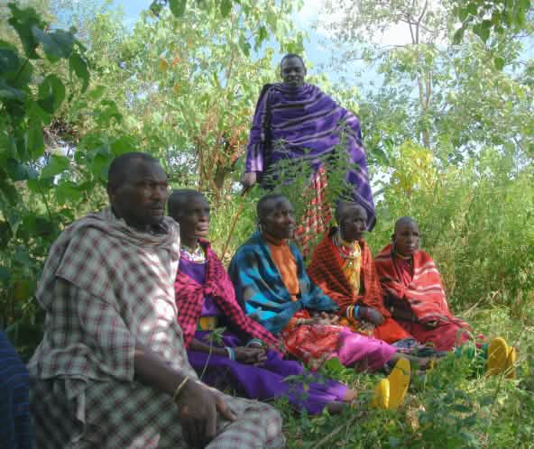 Un grupo de hombres masái sentados en la hierba  con coloridas vestimentas