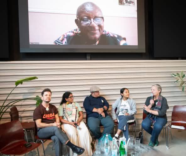 Seis personas protagonizan una conversación sobre un escenario, una de ellas desde una pantalla