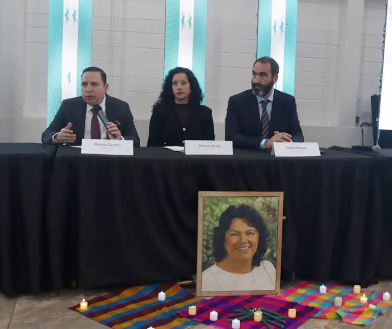 Mesa de los tres integrantes de GIEI, tras un retrato de Berta Cáceres