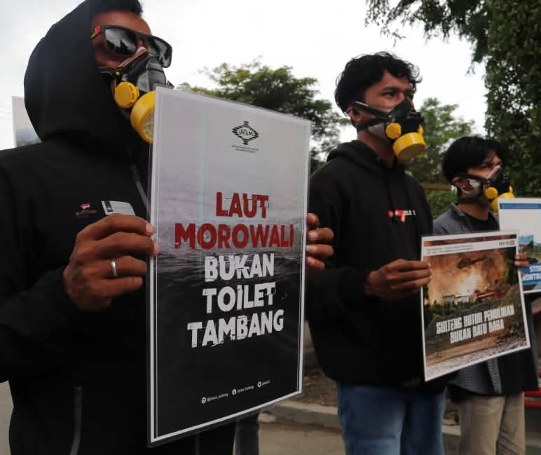 Tres activistas de Jatam con pancartas de protesta en las que se lee en indonesio "El mar de Morowali no es un retrete para la minería"