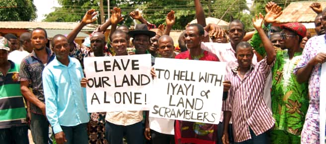 En protesta contra Okomu Oil Palm Oil en Nigeria, algunos afectados sostienen pancartas con leyendas como "Dejen nuestras tierras en paz" y otras