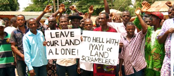 En protesta contra Okomu Oil Palm Oil en Nigeria, algunos afectados sostienen pancartas con leyendas como "Dejen nuestras tierras en paz" y otras