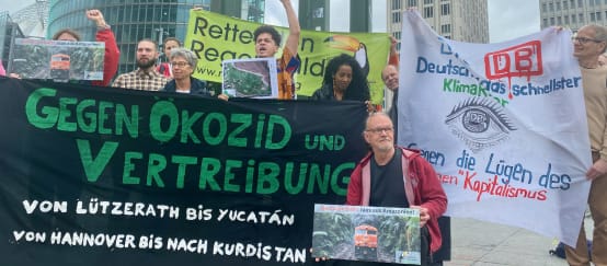 Manifestación en Potsdamer Platz, Berlín, frente a la sede de DB, mayo 2024 (© Stefanie Hess) Un grupo de personas protesta con grandes pancartas de varias organizaciones, delante de unos edificios