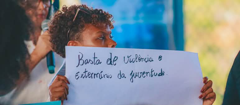 Joven sostiene pancarta en la que se lee "Basta de violencia y exterminio de la juventud"