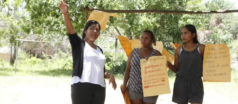 Tres participantes en un taller del Movimiento Xingu Vivo para Siempre sostienen carteles