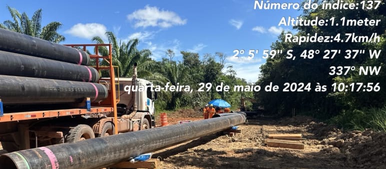 Un camion trailer con tubos y tubos descargados en el suelo en una obra de construcción en el medio de la selva Amazónica
