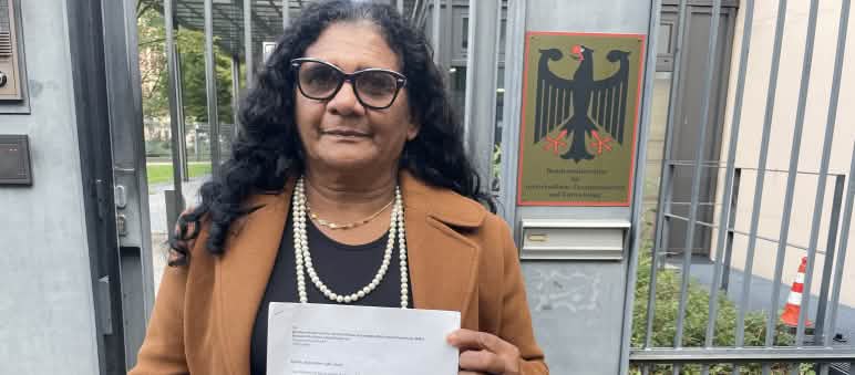 Marli Borges, mujer quilombola, con una carta frente a la entrada enrejada del Ministerio Federal de Desarrollo alemán (BMZ)