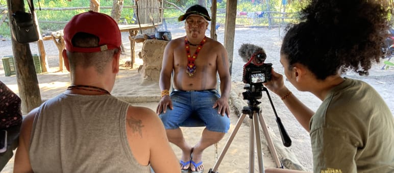 Dos periodistas de The Intercept de espaldas durante la entrevista en vídeo con el líder indígena Itahu Ka'apor, quien se encuentra de frente.