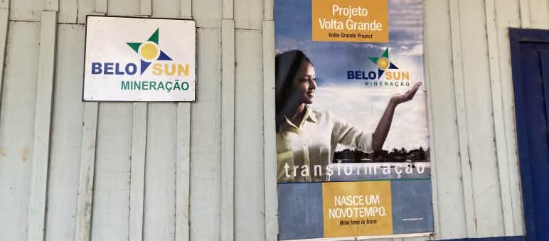 Un cartel de la empresa minera Belo Sun y un cartel publicitario de la empresa en la pared de una cabaña de madera