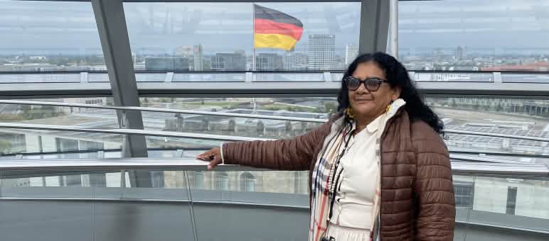 Marli Borges, mujer quilombola, en la cúpula de cristal del Bundestag alemán, con la bandera federal al fondo.