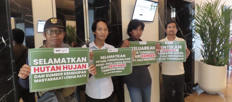 Cuatro hombres sostienen pancartas con leyendas que dicen "Salven la selva y las fuentes de sustento de las personas de Loeha Raya"