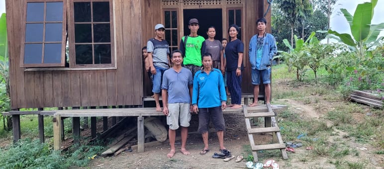 Nueve personas, incluido un representante de Salva la Selva, delante de una casa de madera