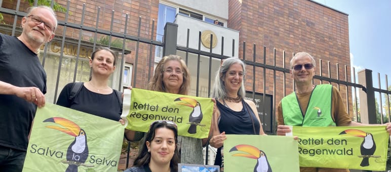 6 personas ante el edificio de la embajada, sosteniendo la petición y las pancartas de Salva la Selva/Rettet den Regenwald