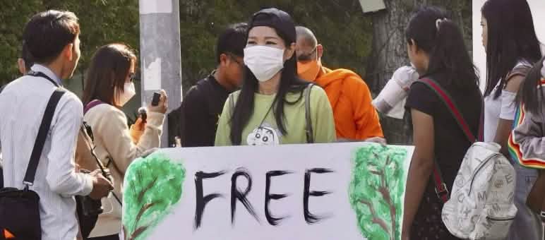 Joven mujer con un gran cartel en el que se lee «¡Liberad a los activistas de Mother Nature!».