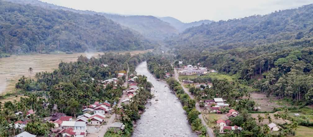 Río atraviesa un pueblo, al fondo se ven montañas