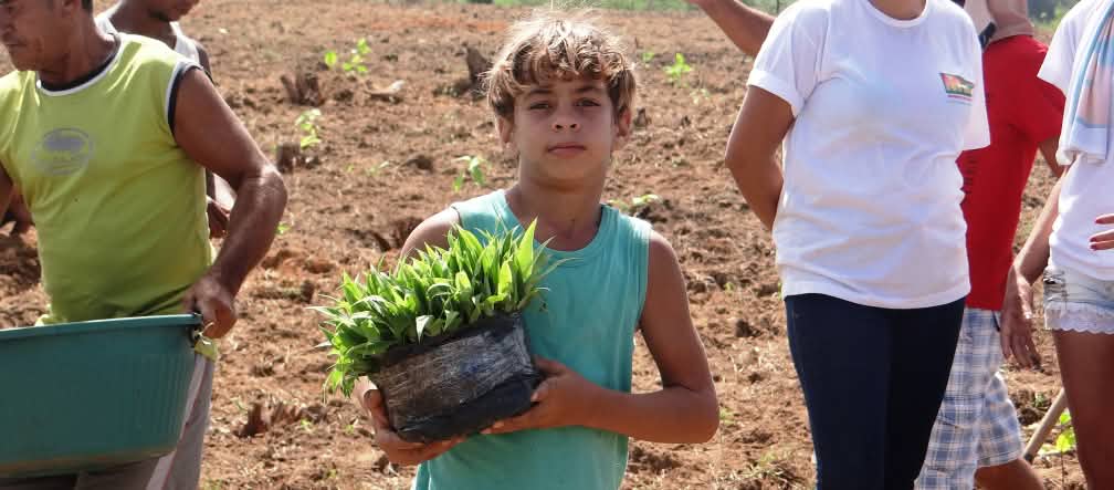 Un grupo de campesinos, entre los que destaca un niño que mira a la cámara en el centro de la imagen, en una jornada de trabajo a punto de sembrar