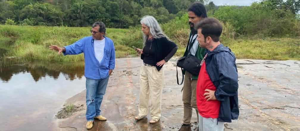 Cuatro personas observan un cuerpo de agua desde su orilla