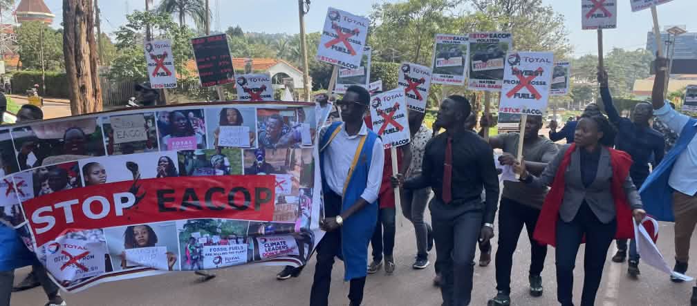 Estudiantes que se manifiestan en Uganda contra el oleoducto sostienen una pancarta de mayor tamaño con la leyenda Stop EACOP y pequeñas pancartas con más mensajes de protesta