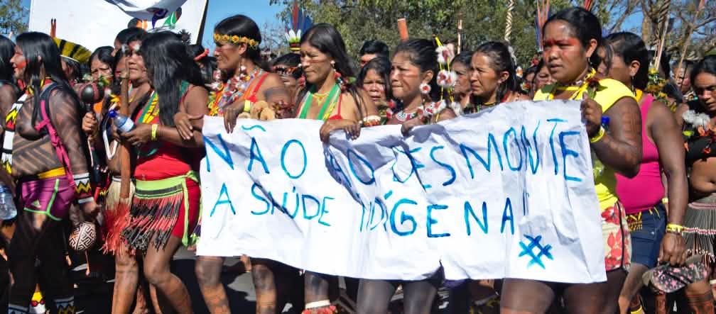 Mujeres indígenas de brasil protestan contra la destrucción de sus territorios con una pancarta en la que dice “Nao ao desmonte” contra la deforestación de la selva tropical