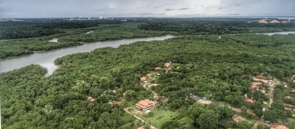 Vista aérea de casas entre la vegetación amazónica abundante y detrás un río con manglares en las orillas en Tauá Mirim, Maranhao, Brasil