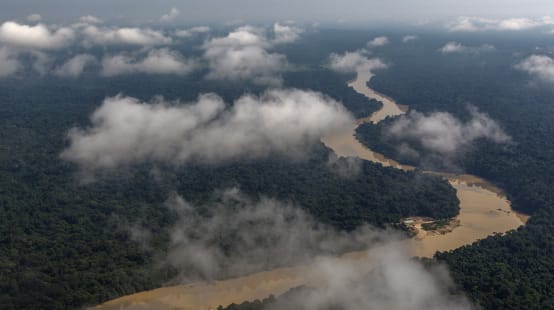 Vista aérea con nubes de un río serpenteando por la selva tropical amazónica