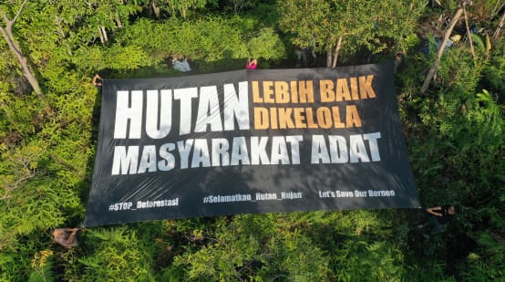 Gran pancarta con el mensaje "Indígenas, los mejores defensores de la selva", en idioma bahasa Indonesia