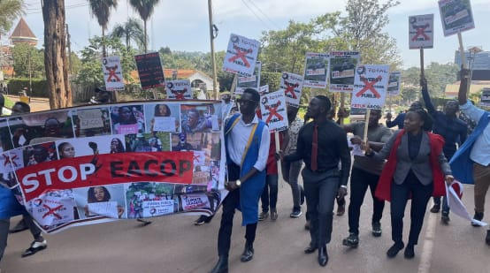 Estudiantes que se manifiestan en Uganda contra el oleoducto sostienen una pancarta de mayor tamaño con la leyenda Stop EACOP y pequeñas pancartas con más mensajes de protesta
