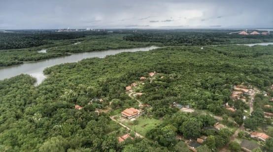 Vista aérea de casas entre la vegetación amazónica abundante y detrás un río con manglares en las orillas en Tauá Mirim, Maranhao, Brasil
